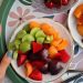 Top view of a colorful fruit platter with cherries, apricots, and plums on a decorative tray.