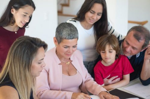 A family discusses real estate documents at home with a realtor, fostering communication and planning.