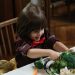 Young child excitedly cutting broccoli during a healthy meal at home.